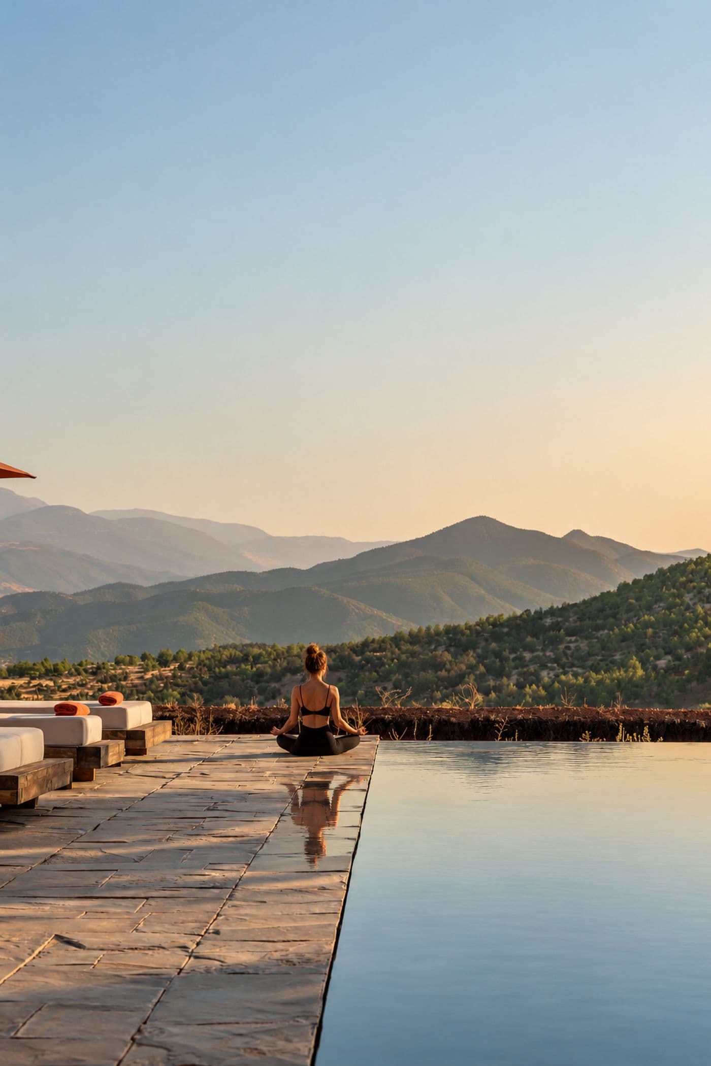 Femme pratiquant la méditation au bord de la piscine à débordement d’Eladâr, face aux montagnes de l’Atlas près de Marrakech
